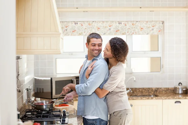 Γυναίκα που αγκαλιάζει τον σύζυγό της, ενώ αυτός είναι το μαγείρεμα — Φωτογραφία Αρχείου