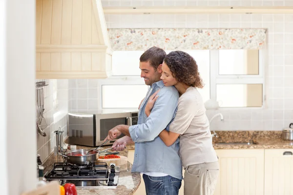 Žena objímala svého manžela, zatímco on je na vaření — Stock fotografie
