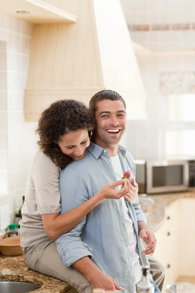 Lovers eating a strawberry in their kitchen — Stock Photo, Image