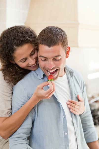 Miłośnicy jedząc truskawki w kuchni — Zdjęcie stockowe