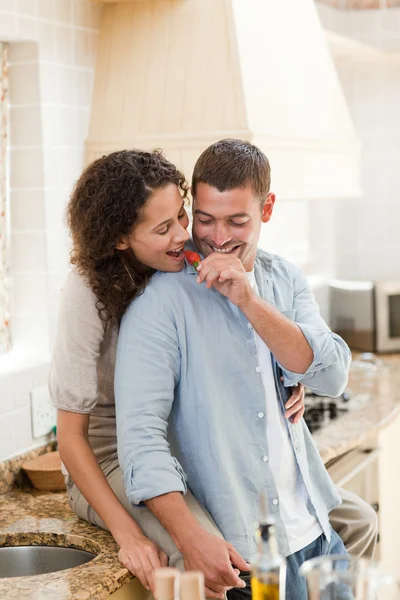 Lovers eating a strawberry in their kitchen — Stock Photo, Image