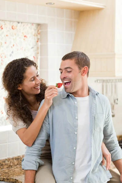 在他们的厨房里吃草莓的恋人 — 图库照片