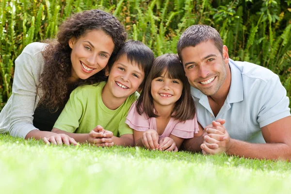 Happy family lying down in the garden — Stock Photo, Image