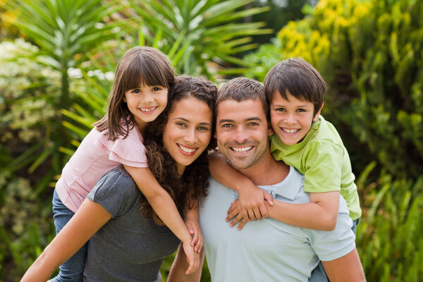 Mother and father giving children a piggyback — Stock Photo, Image