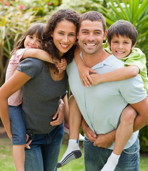 Mother and father giving children a piggyback — Stock Photo, Image