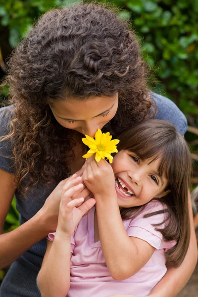Madre oliendo una flor con su hija — Foto de Stock
