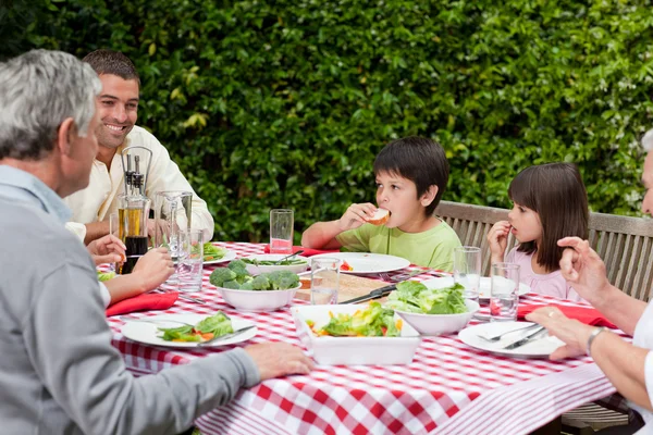 Lycklig familj äta i trädgården — Stockfoto