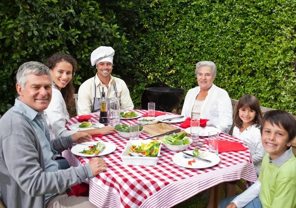 Счастливая семья ест в саду — стоковое фото