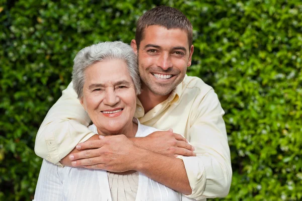 Mann umarmt seine Mutter im Garten — Stockfoto