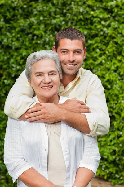 Мужчина обнимает свою мать в саду — стоковое фото