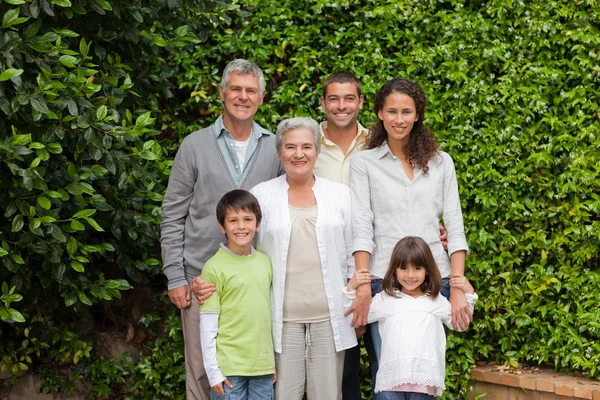 Porträtt av en lycklig familj titta på kameran i trädgården — Stockfoto
