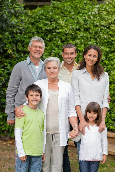 Porträt einer glücklichen Familie, die im Garten in die Kamera blickt — Stockfoto