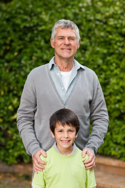 Nonno con suo nipote che guarda la macchina fotografica in giardino — Foto Stock