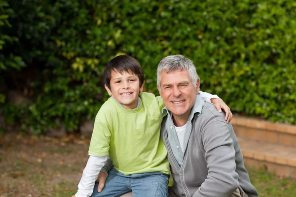 Grandfather with his grandson looking at the camera in the garde — Stock Photo, Image