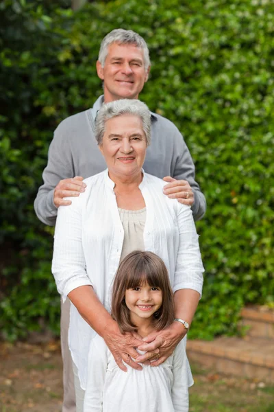 Família sorrindo olhando para a câmera no jardim — Fotografia de Stock