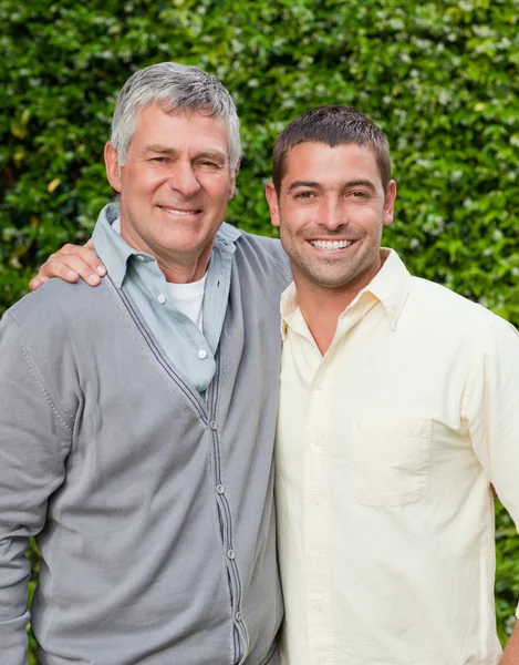 Vater und Sohn blicken im Garten in die Kamera — Stockfoto