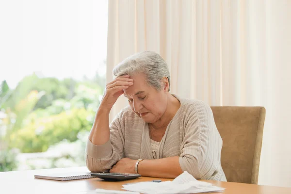 Вышедшая на пенсию женщина рассчитывает свои счета — стоковое фото
