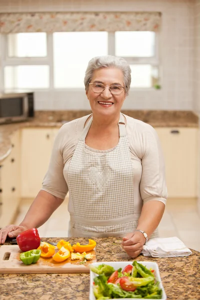 Gepensioneerde vrouw kijken naar de camera in de keuken — Stockfoto
