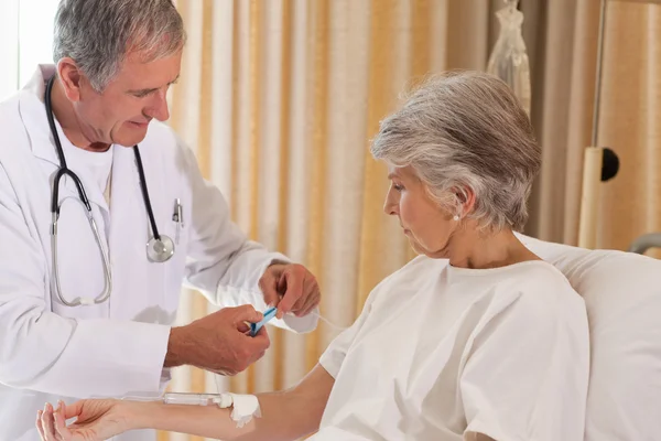 Doutor colocando um gotejamento no braço de seu paciente — Fotografia de Stock