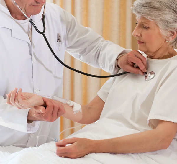 Senior arts nemen de hartslag van zijn patiënt — Stockfoto