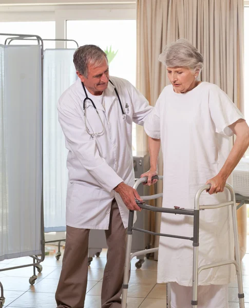 Ανώτερος γιατρός βοηθώντας τον ασθενή να περπατήσει — Stockfoto