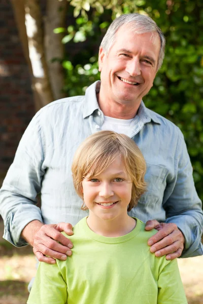 Grandfather with his grandson looking at the camera in the garde — Stock Photo, Image
