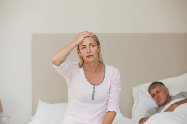 Женщина страдает головной болью, пока ее муж спит — стоковое фото