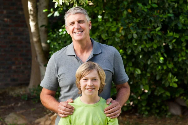 Otec a jeho syn se dívají do kamery na zahradě — Stock fotografie