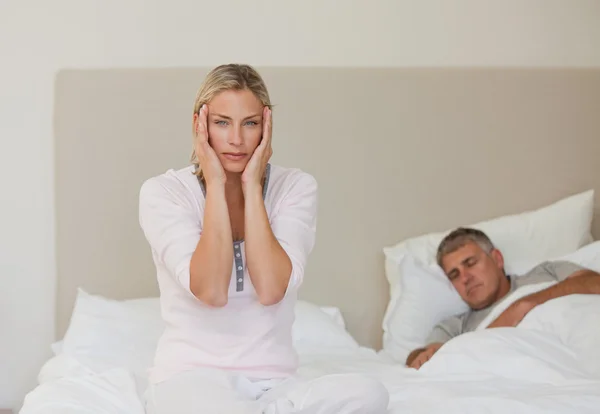 Женщина страдает головной болью, пока ее муж спит — стоковое фото