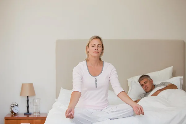 Härlig kvinna utövar yoga på hennes säng — Stockfoto