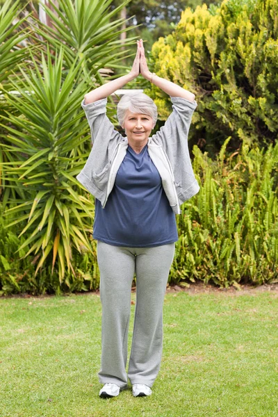 Reife Frau bei ihren Stretches im Garten — Stockfoto
