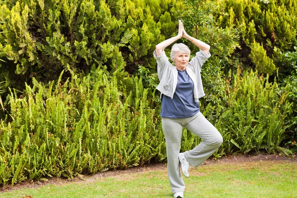 Mature woman doing her streches in the garden — Stock Photo, Image