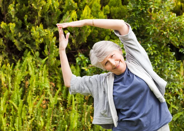 Reife Frau bei ihren Stretches im Garten — Stockfoto