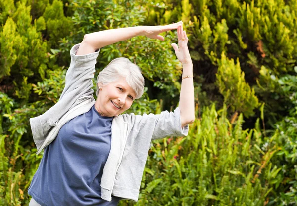 Mature woman doing her streches in the garden — Stock Photo, Image