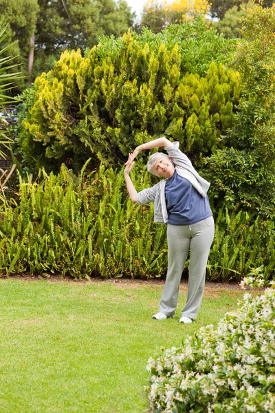 Retired woman doing her streches in the garden — Stock Photo, Image