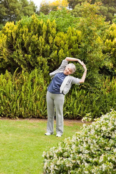 Retired woman doing her streches in the garden — Stock Photo, Image