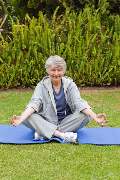 Retired woman practicing yoga in the garden — Stock Photo, Image