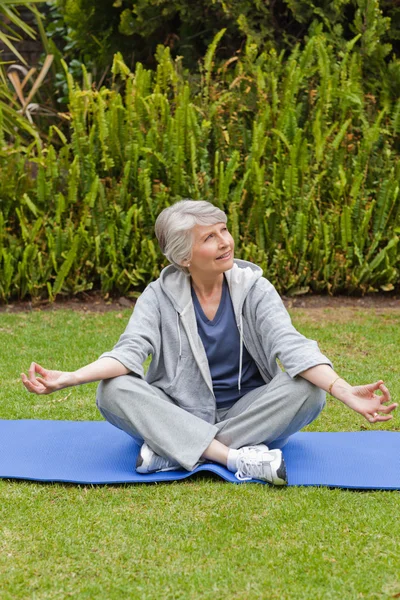 Mulher aposentada praticando ioga no jardim — Fotografia de Stock