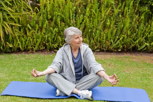 Mulher aposentada praticando ioga no jardim — Fotografia de Stock