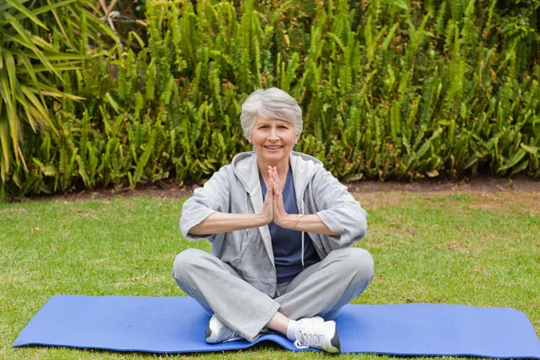 Žena cvičí jógu v zahradě v důchodu — Stock fotografie