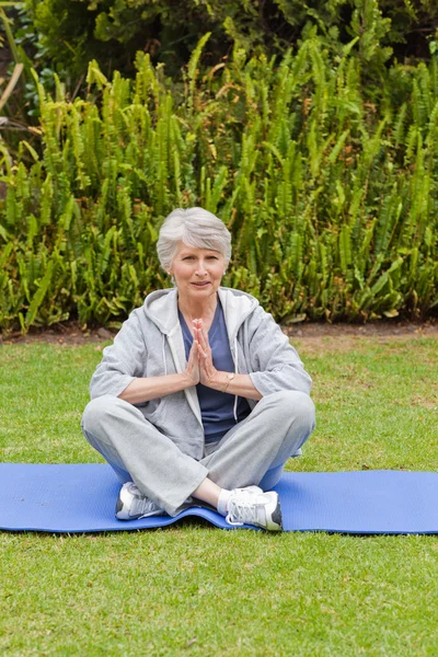 Emeryturę kobieta praktykowania jogi w ogrodzie — Zdjęcie stockowe