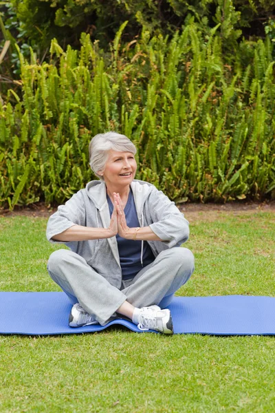 Pensionerad kvinna utövar yoga i trädgården — Stockfoto