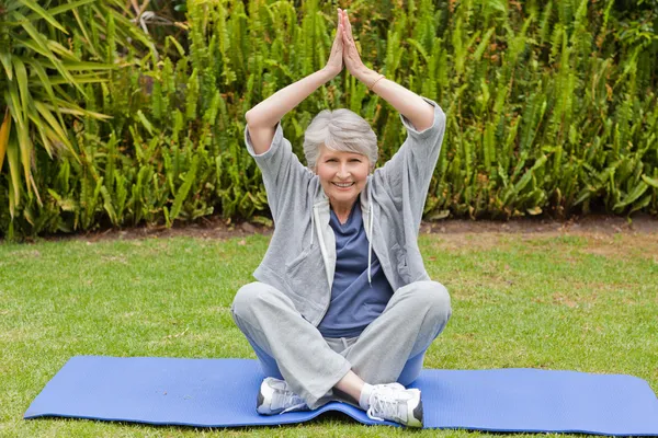 Senior woman doing her streches in the garden — Stock Photo, Image