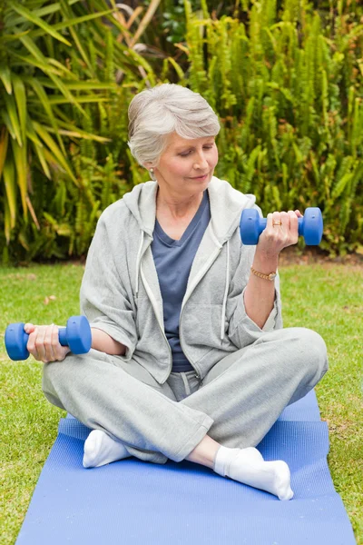 Pensionerad kvinna gör hennes övningar i trädgården — Stockfoto