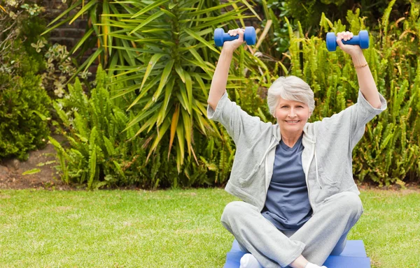 Retired woman doing her exercises in the garden — Stock Photo, Image