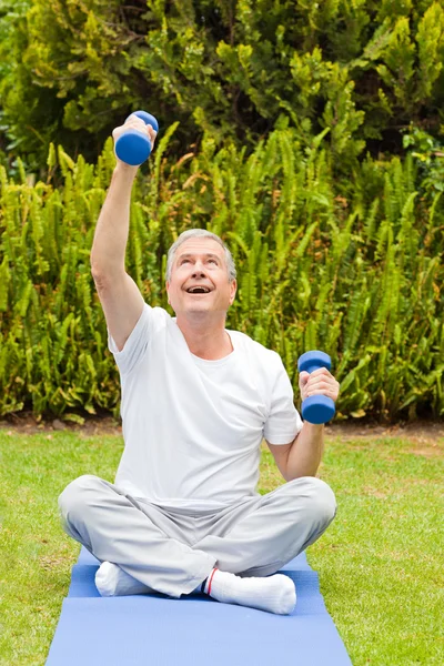 Пенсионер делает упражнения в саду — стоковое фото