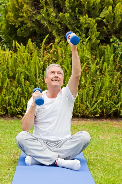 Pensionerad man gör sina övningar i trädgården — Stockfoto