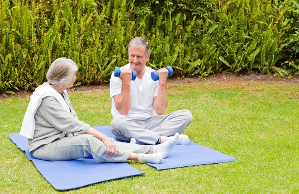 Starsza para robi ich ćwiczenia w ogrodzie — Zdjęcie stockowe