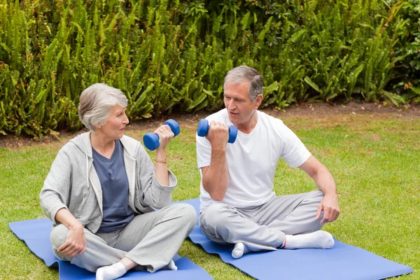 Mature couple doing their exercises in the garden — Stock Photo, Image