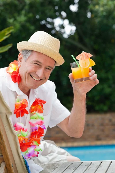 Mature man drinking a cocktail beside the swimming pool — Stock Photo, Image